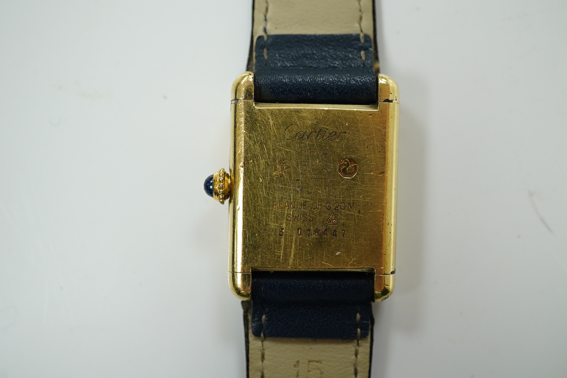 A lady's gilt 925 Must De Cartier manual wind wrist watch, with lapis lazuli rectangular dial and cabochon sapphire set winding crown, on an associated leather strap, case diameter 20mm, no box or papers. Condition - poo